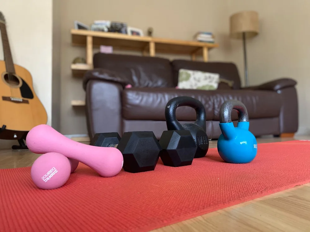 Home workout kit on an exercise mat: dumbbells and kettlebells.