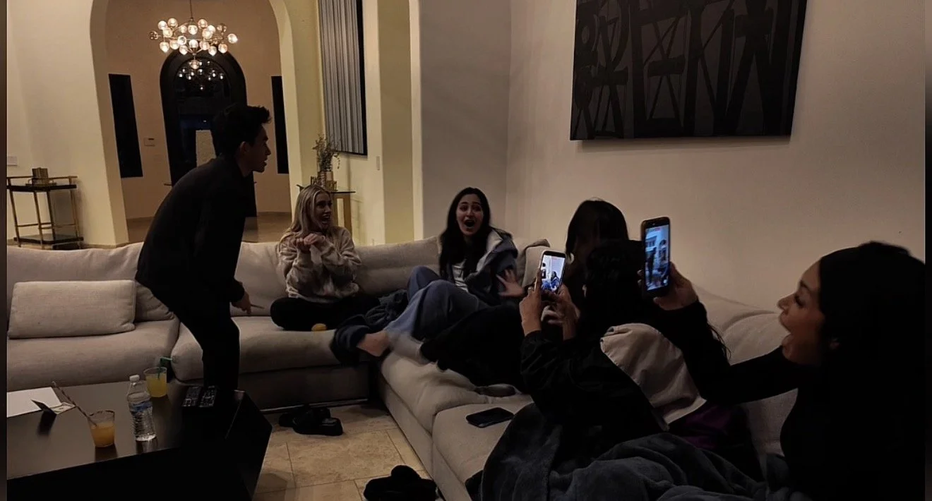 Jacob Martinez performing at a living room party while guests film on their phones