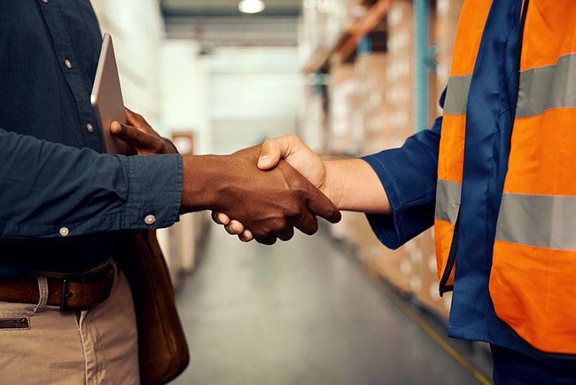 Two men shaking hands in a warehouse of a wholesale B2B business.