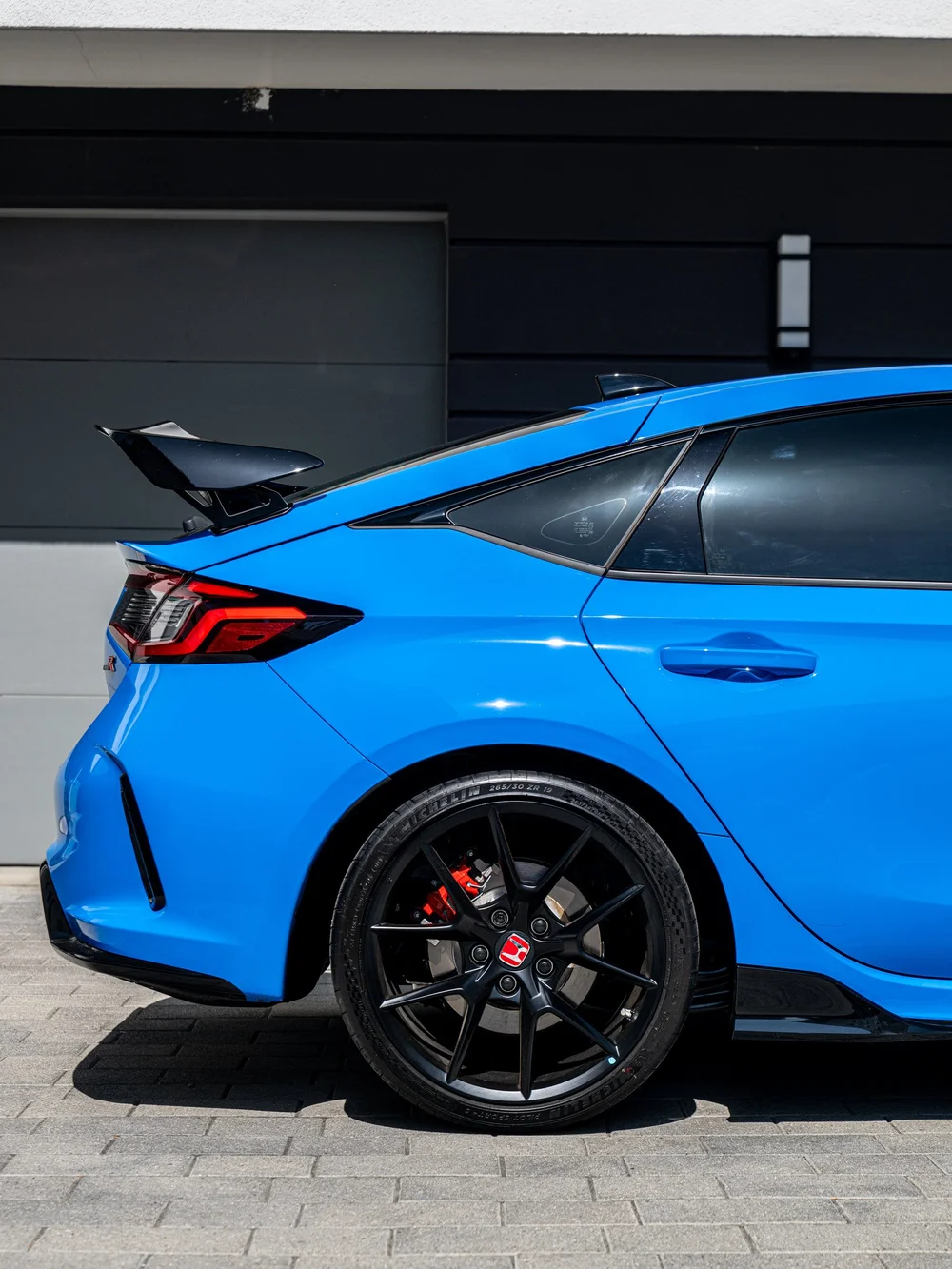 Rear quarter and factory rear wing detail on a Boost Blue Pearl Civic Type R