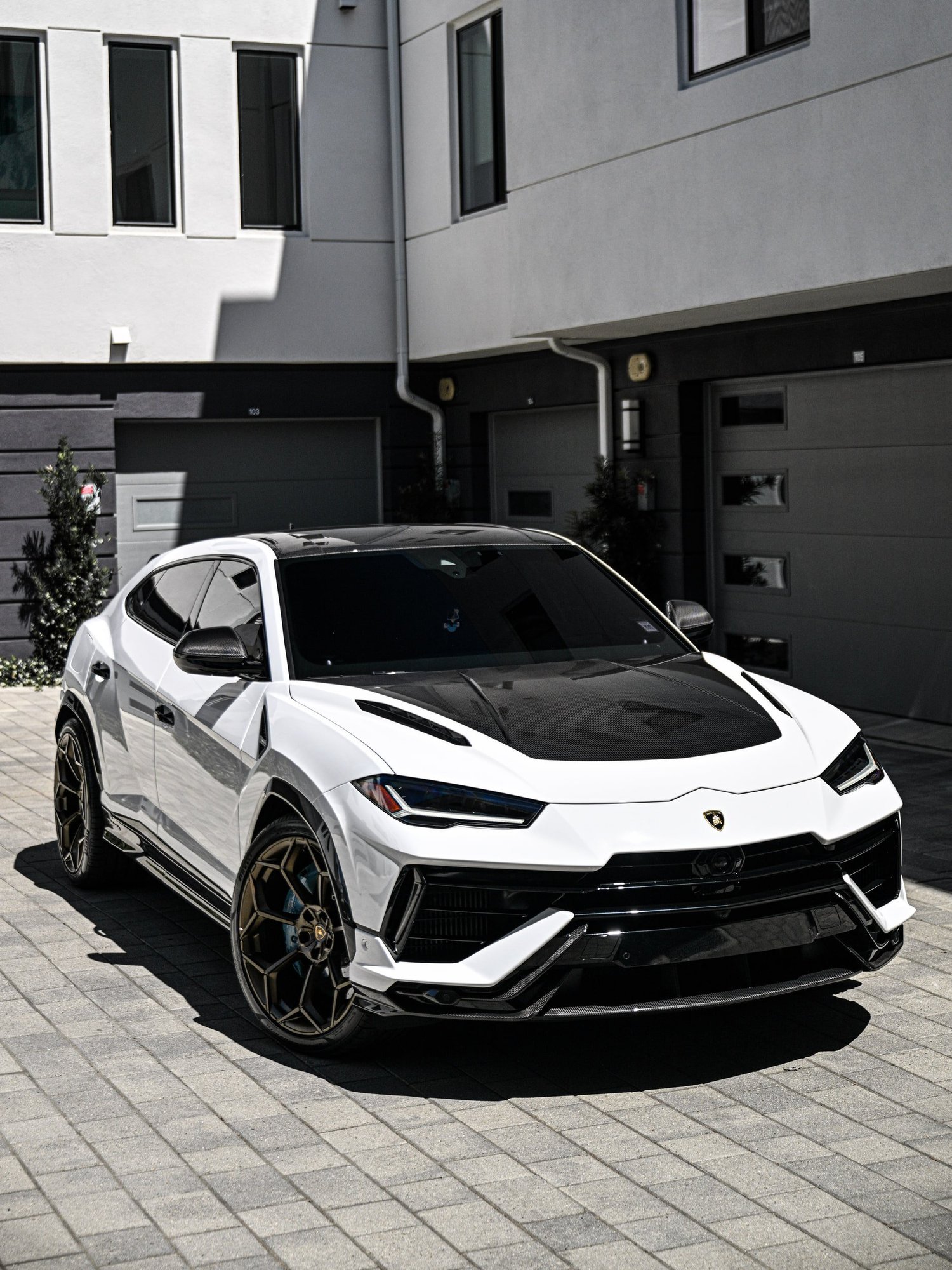 White Lamborghini Urus Performante in a complete front three-quarter view with a dark hood and bronze-toned wheels