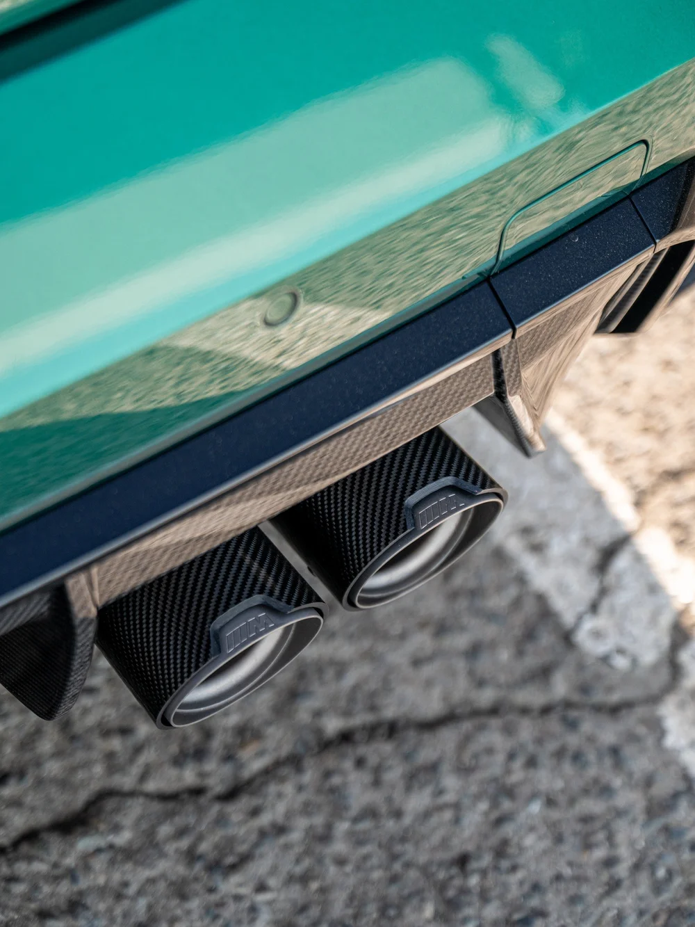 Close-up of the M Performance carbon rear diffuser and adjacent exhaust outlets on the green M3