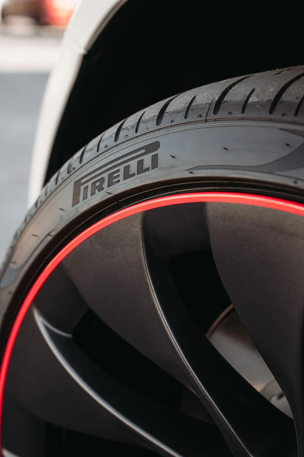 Close wheel and tire detail on the Tesla Model 3 showing a red accent around the dark wheel rim
