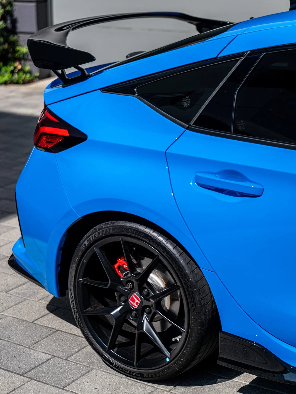 Rear wheel, quarter panel and rear wing detail on a Boost Blue Pearl Civic Type R
