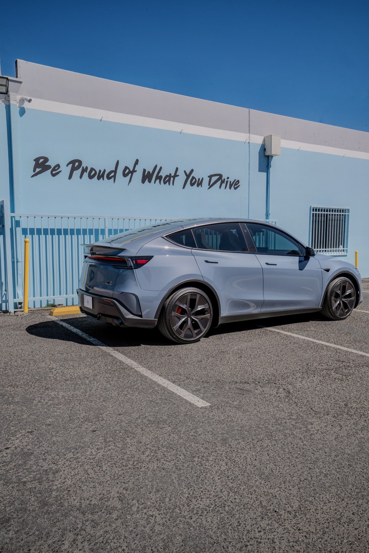 Glacier Blue Model Y Performance from the rear passenger-side quarter with dark wheels and factory privacy glass