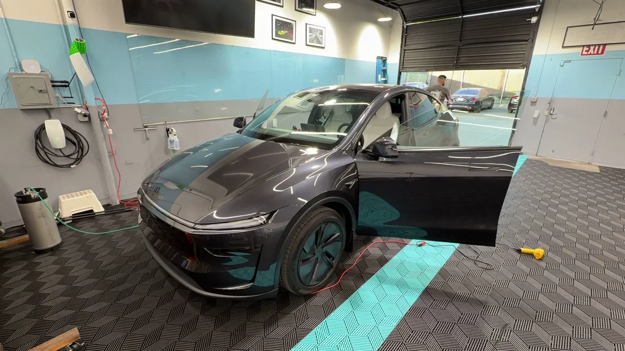 2026 Tesla Model Y Premium — video frame showing the front and side with a door open inside the studio