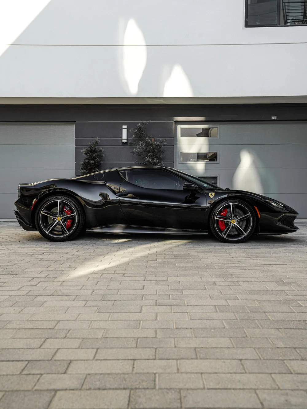 Complete side profile of the black Ferrari 296 GTB with dark five-spoke wheels