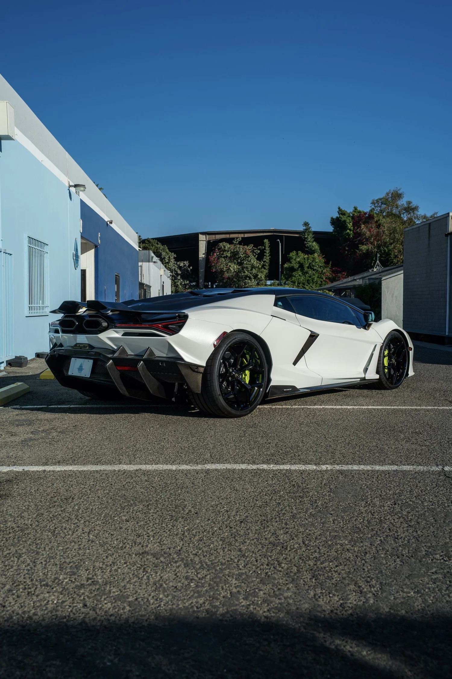 White Lamborghini Revuelto from the rear three-quarter angle beside Toyz Detail Studio.