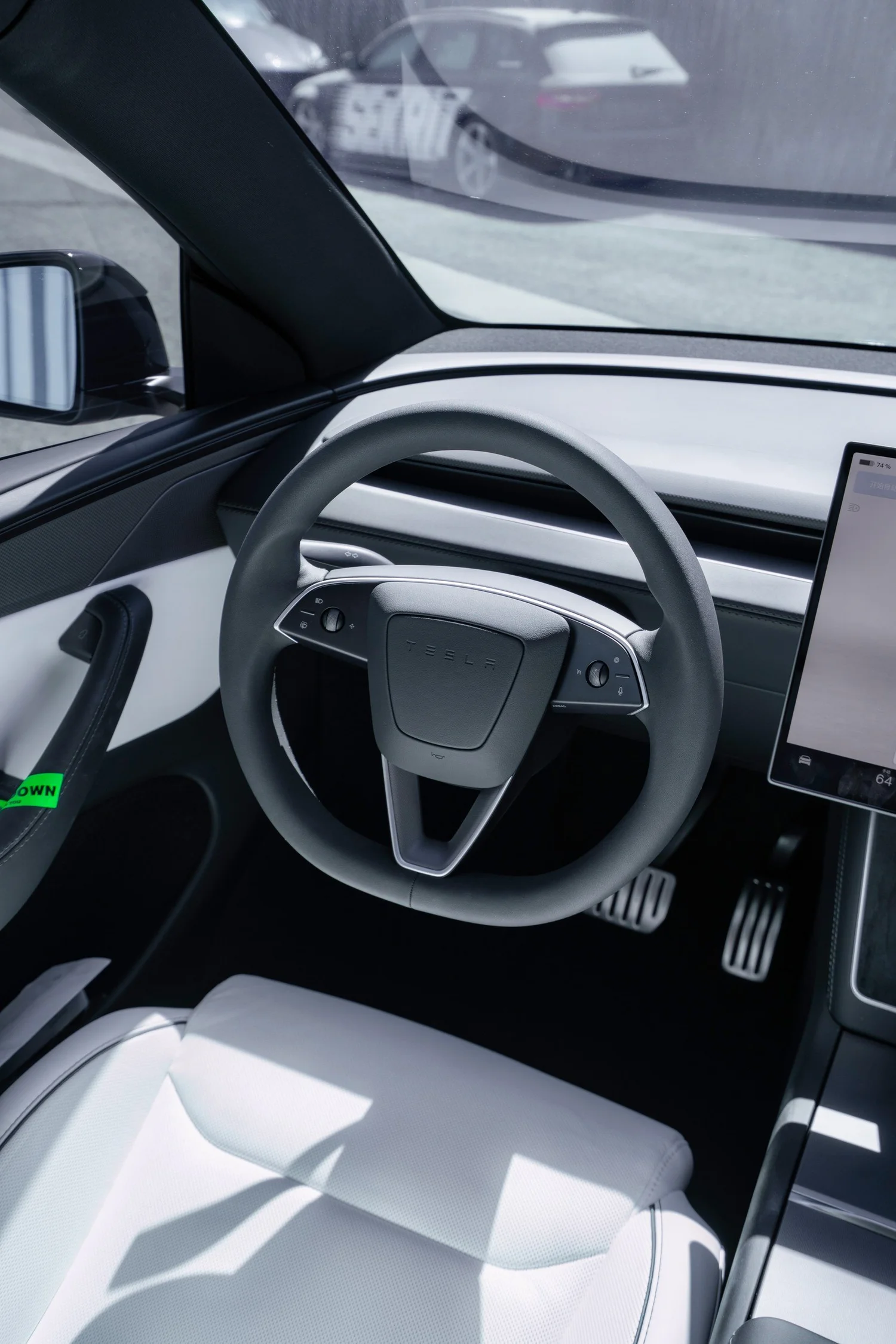 Tesla Model Y Performance steering wheel, pedals and white driver seat