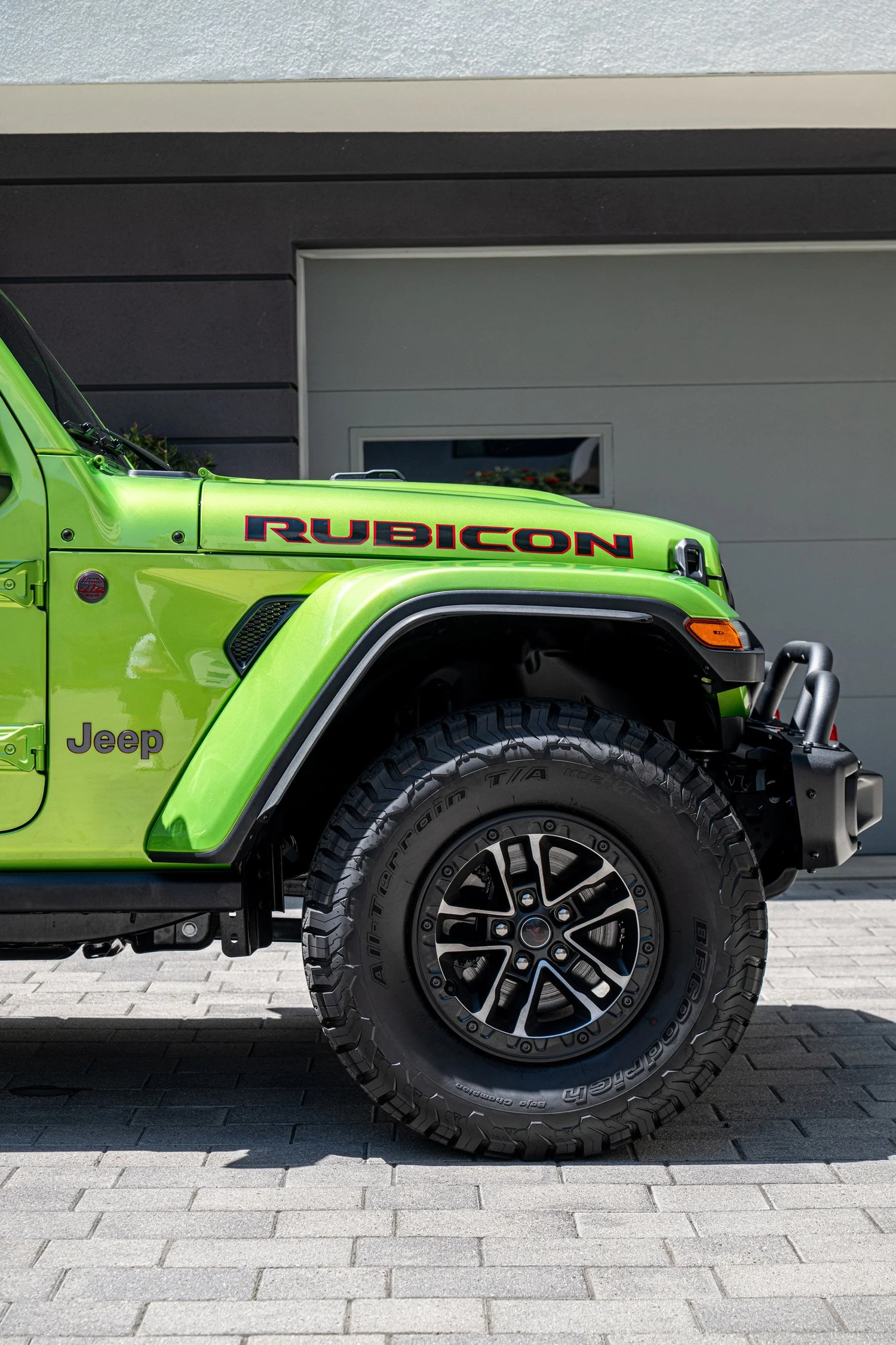 Front wheel and Mojito-painted fender of the Wrangler Rubicon beside its textured black fender flare