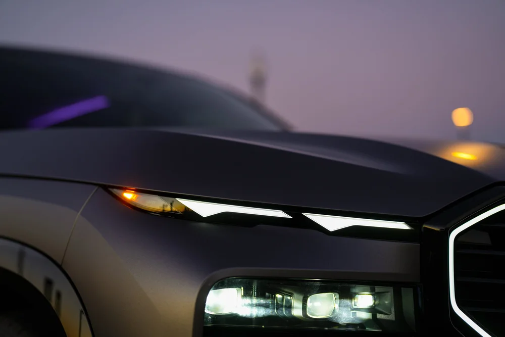 Front-lamp close-up showing a slim upper light strip, an amber corner light and rectangular headlamps below the grey hood.
