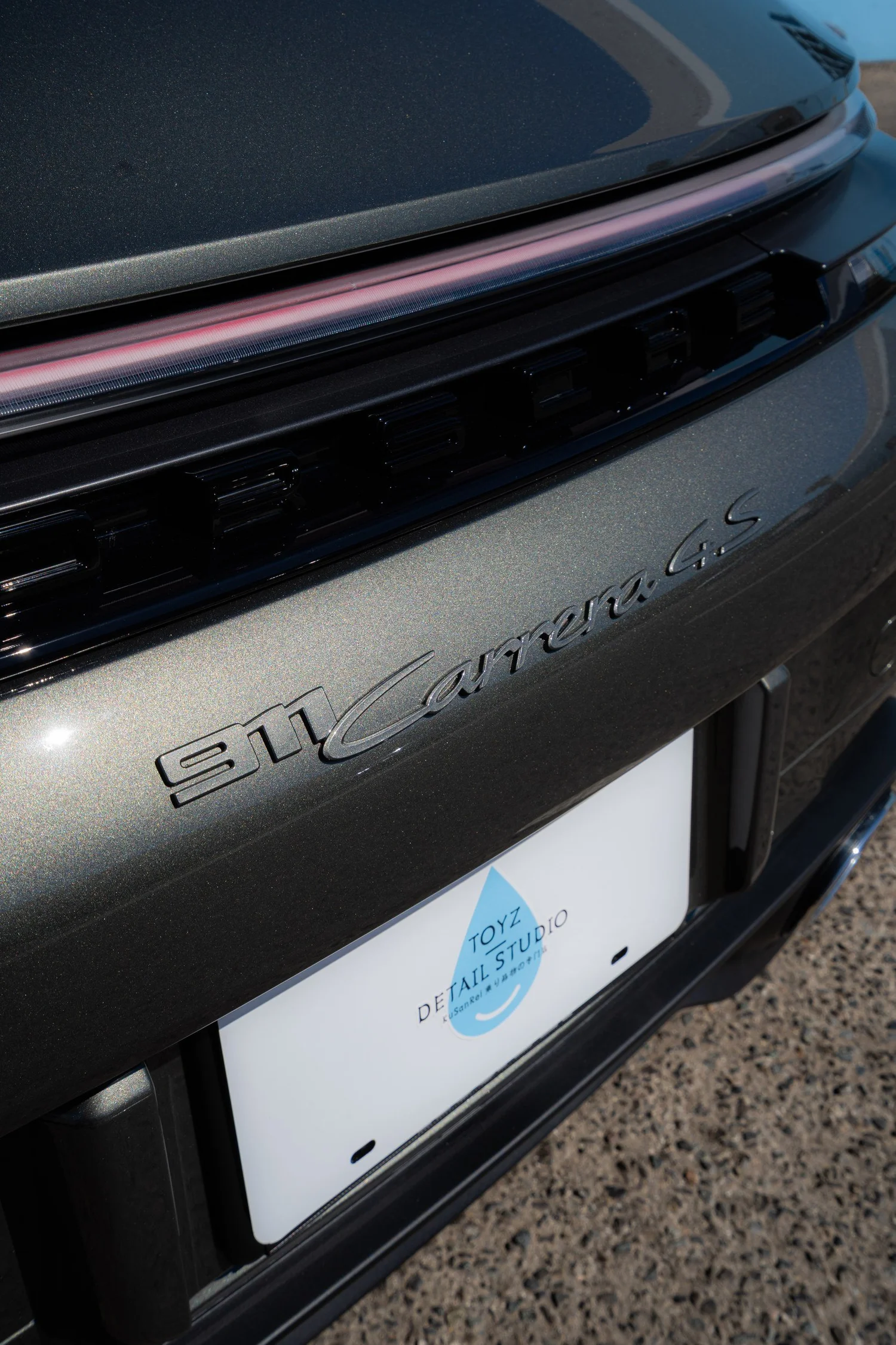 Rear light bar and 911 Carrera 4S badging above the Toyz Detail Studio plate frame on the Vanadium Grey Cabriolet.