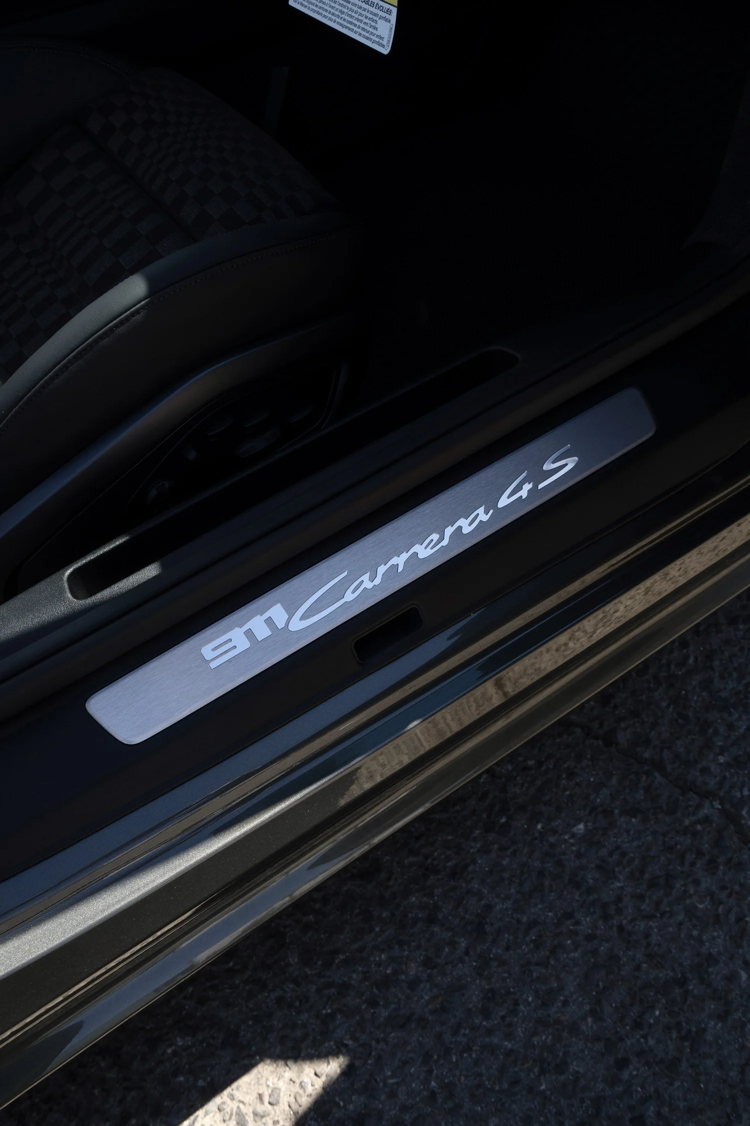 Porsche 911 Carrera 4S door-sill lettering beside the dark cabin and open doorway.