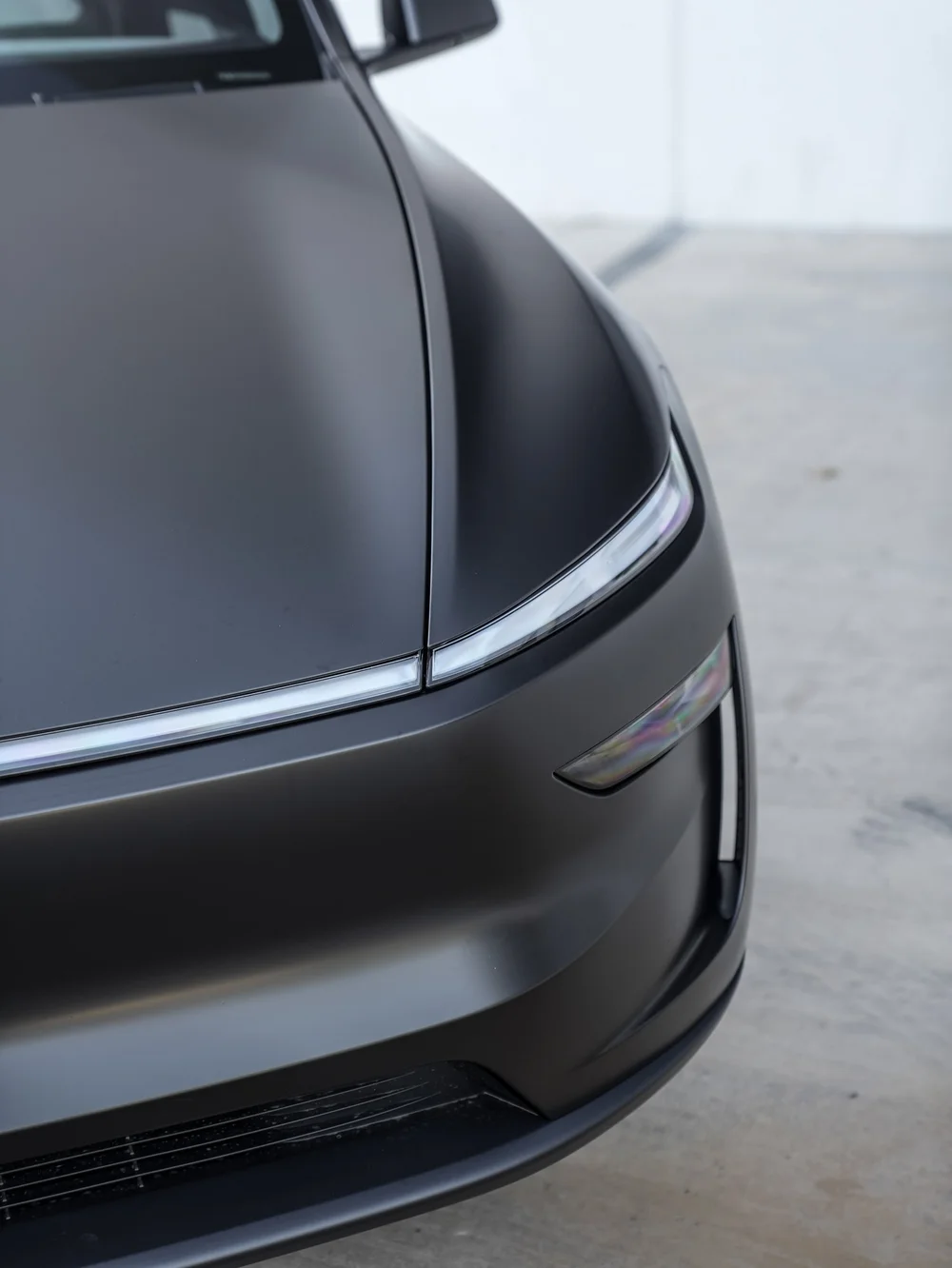 Tesla Model Y with 3M Satin Black vinyl, close hood edge and front light-strip detail