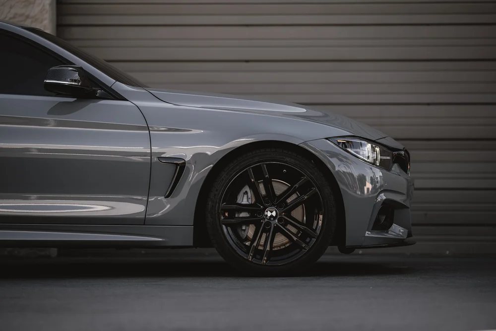 Horizontal side detail of the BMW 440i powder-coated front wheel beneath the Nardo Grey fender