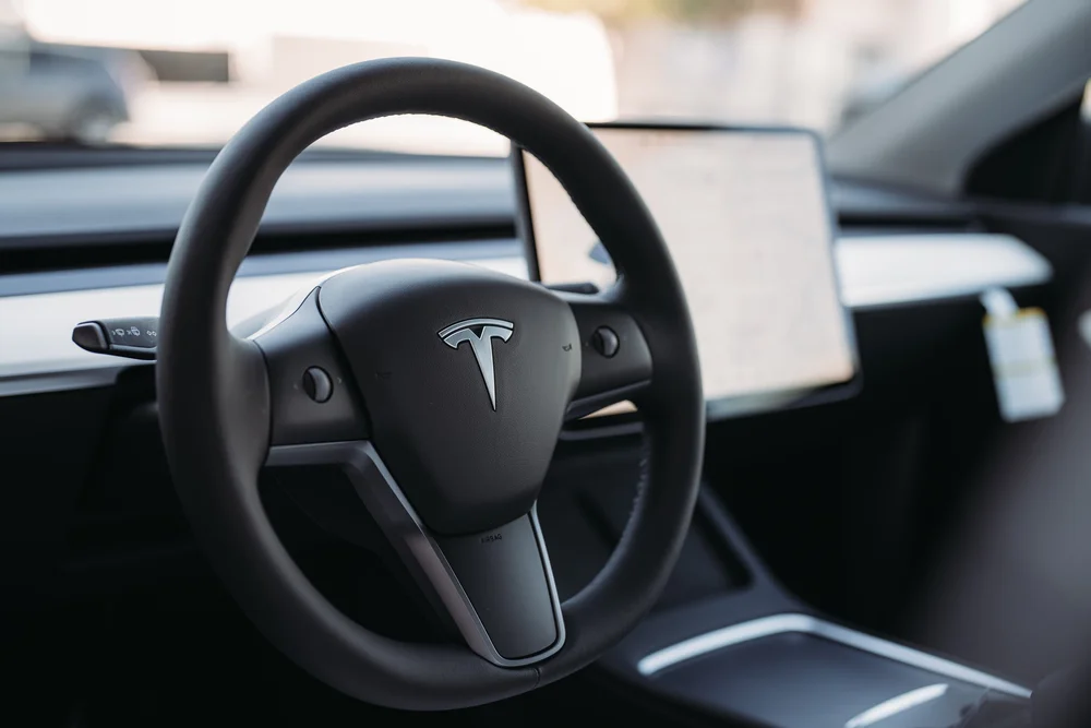 Landscape interior photograph of the Tesla Model Y steering wheel and central screen