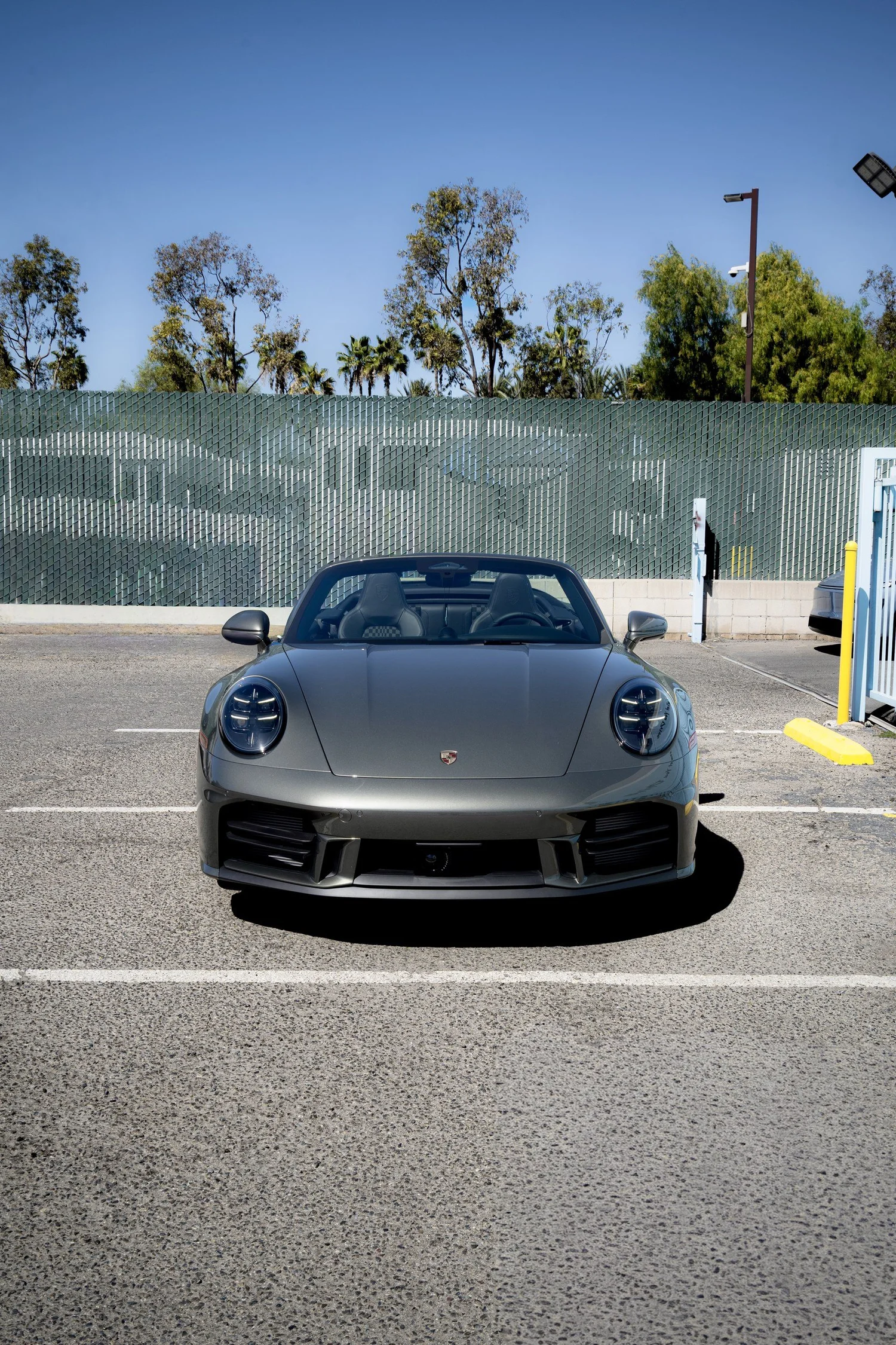 Straight-on front view of the Vanadium Grey Porsche 911 Carrera 4S Cabriolet with the roof lowered in the Toyz parking area.