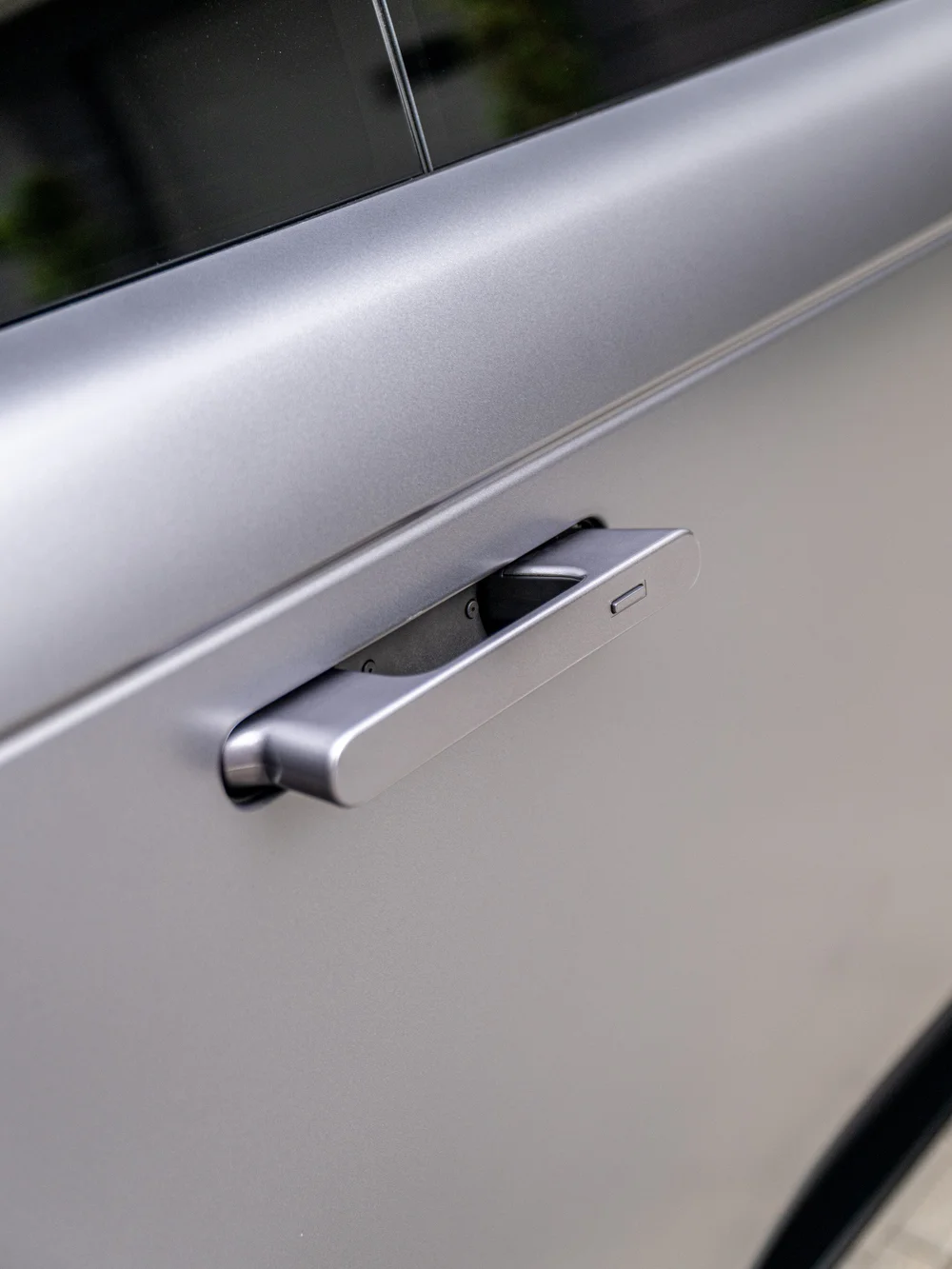 Angled close-up of the Range Rover's extended flush door handle against the satin Eiger Grey door panel.