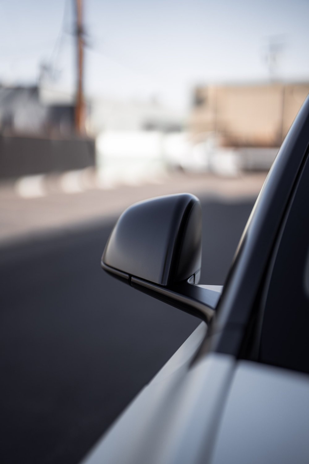 Mirror housing and front-door detail beside the Satin Pearl White Tesla Model Y bodywork