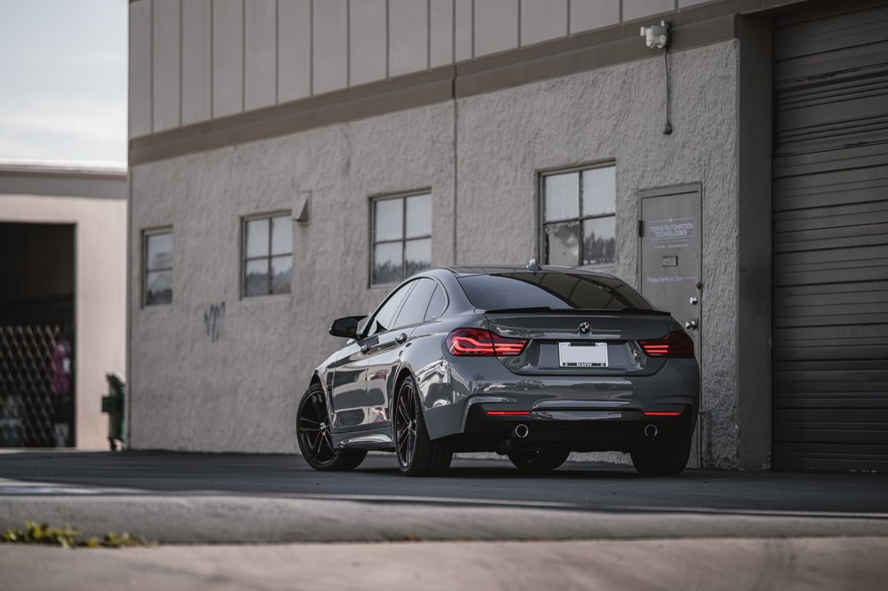 Wide rear three-quarter view of the Nardo Grey BMW 440i showing the rear body and powder-coated wheels
