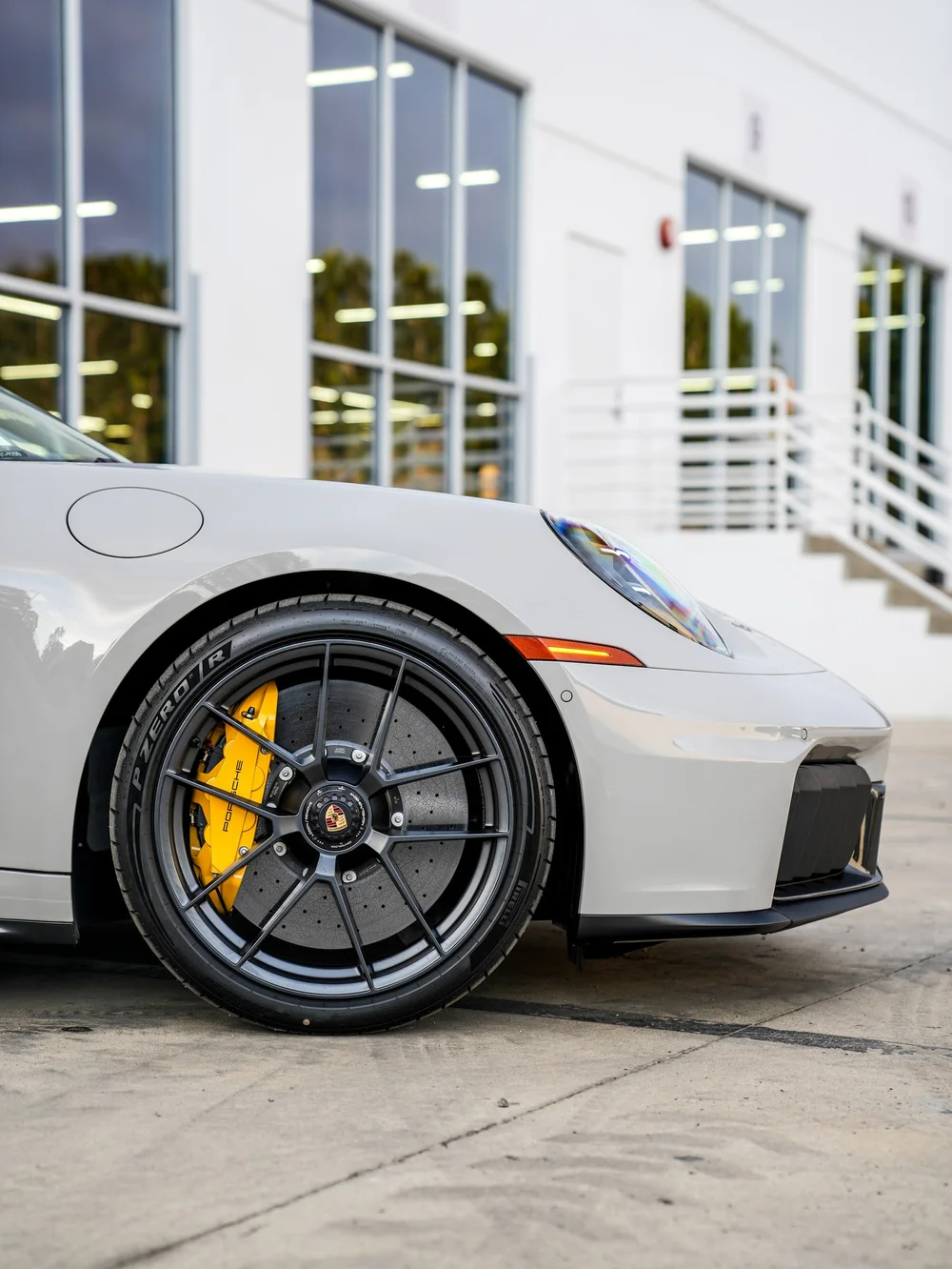 Porsche front wheel and yellow brake caliper beneath the light front fender