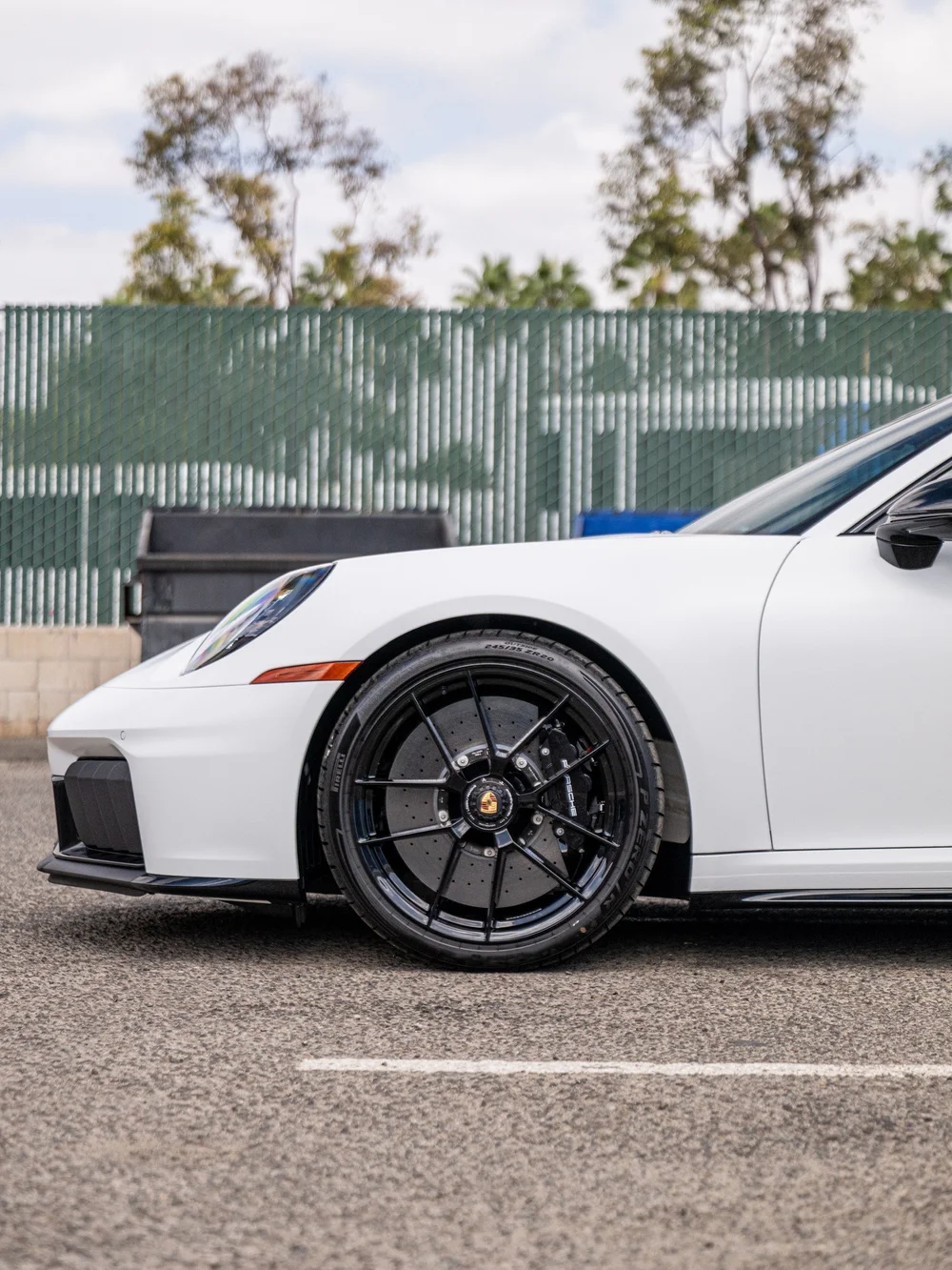 Front-side detail of a 2026 Porsche 911 Carrera 4 GTS with center-lock front wheel and satin-white XPEL STEALTH finish
