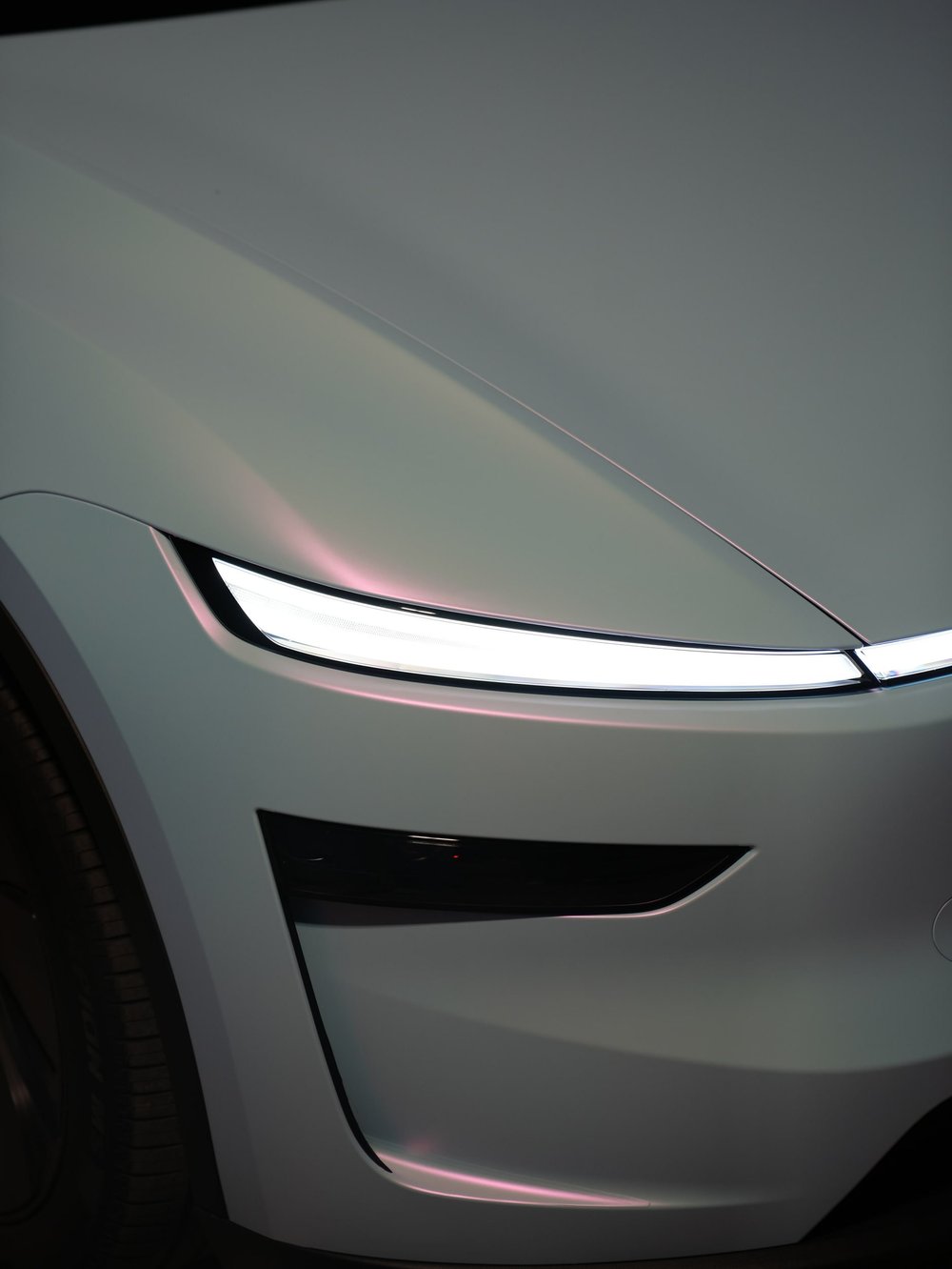 Front headlight and hood-corner detail of a Tesla Model Y with white-to-blue color-shifting vinyl