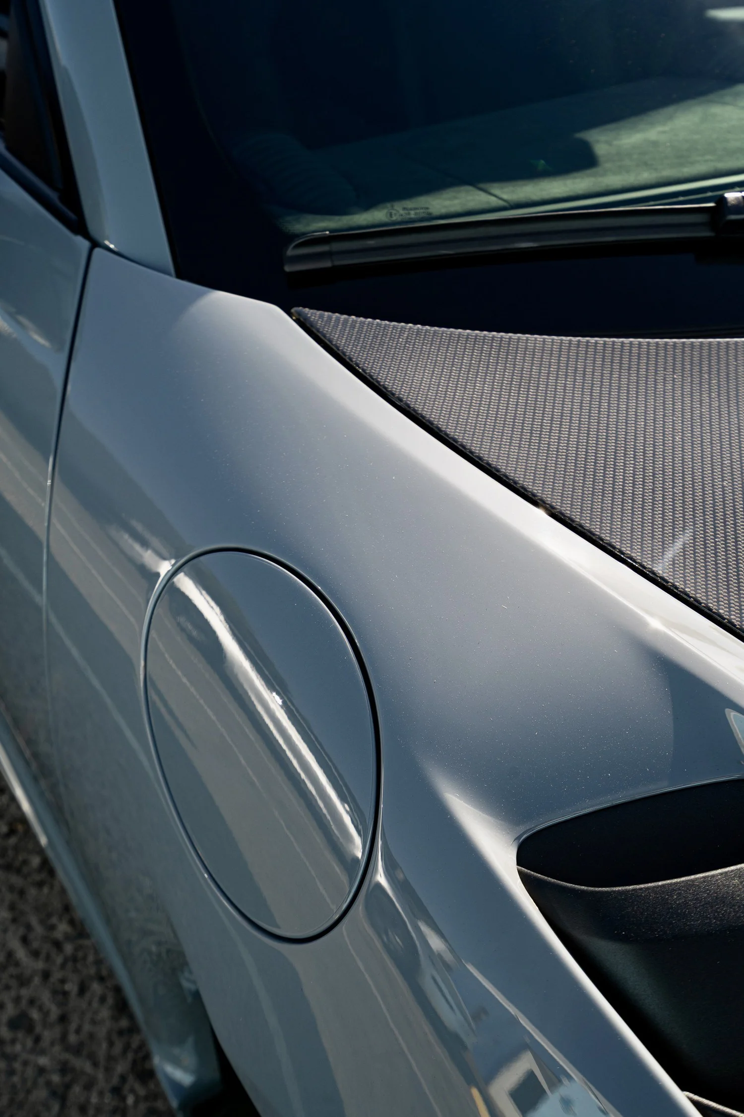 Arctic Grey front fender and fuel-filler flap beside the exposed carbon hood and windshield of the GT4 RS.