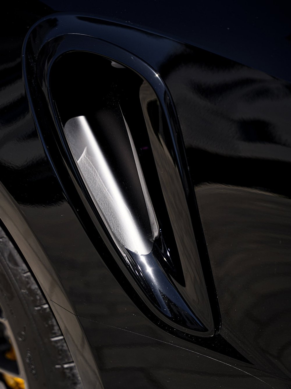 Close view of the Turbo S side air intake and surrounding Jet Black Metallic rear-quarter panel.