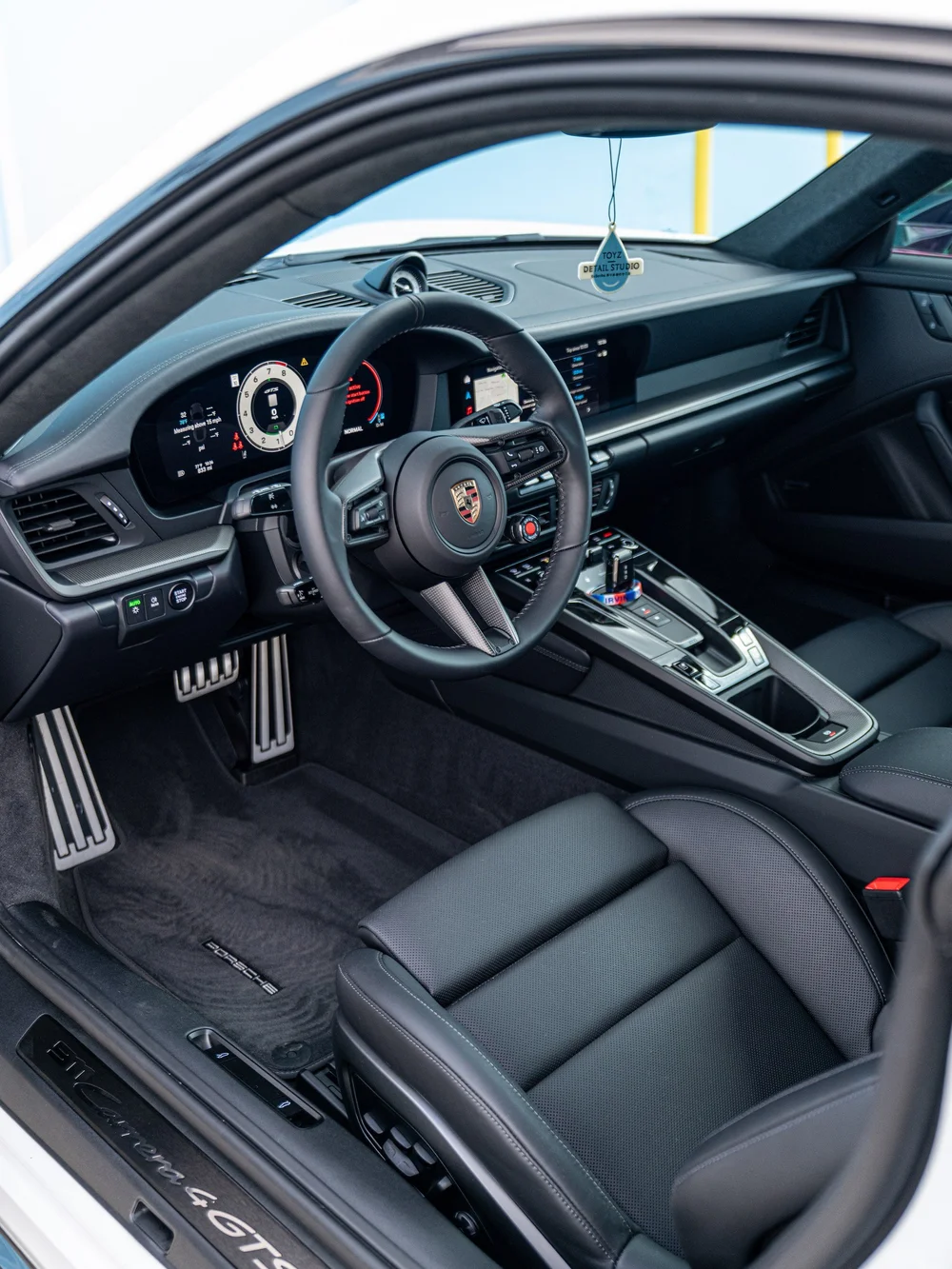 Driver cockpit of a 2026 Porsche 911 Carrera 4 GTS with steering wheel, instrument panel, center console and front seat