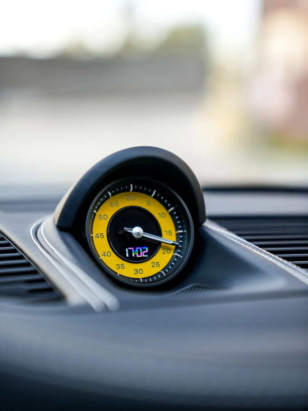 Yellow Porsche dashboard clock in a dark instrument housing