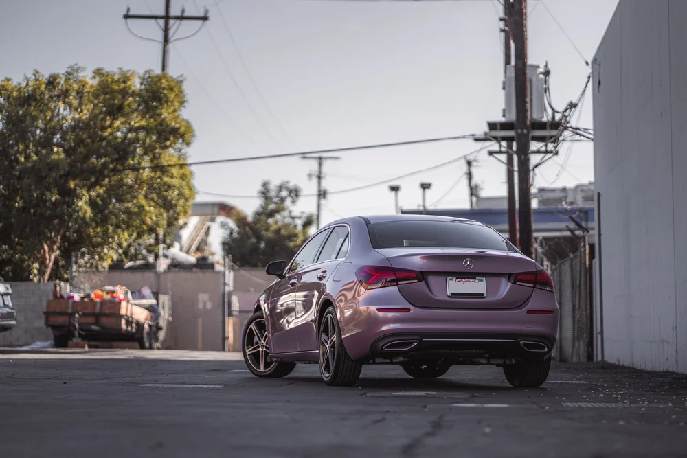 Wide rear three-quarter view of the Frozen Berry Mercedes-Benz A 220 outside the studio