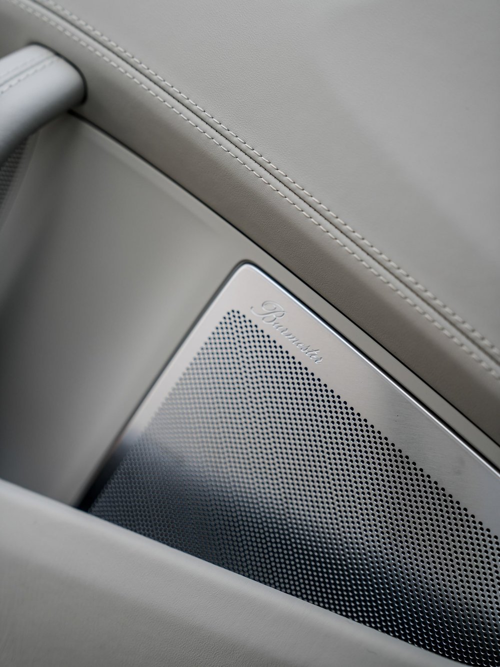 Porsche door stitching beside a metallic speaker grille and light trim
