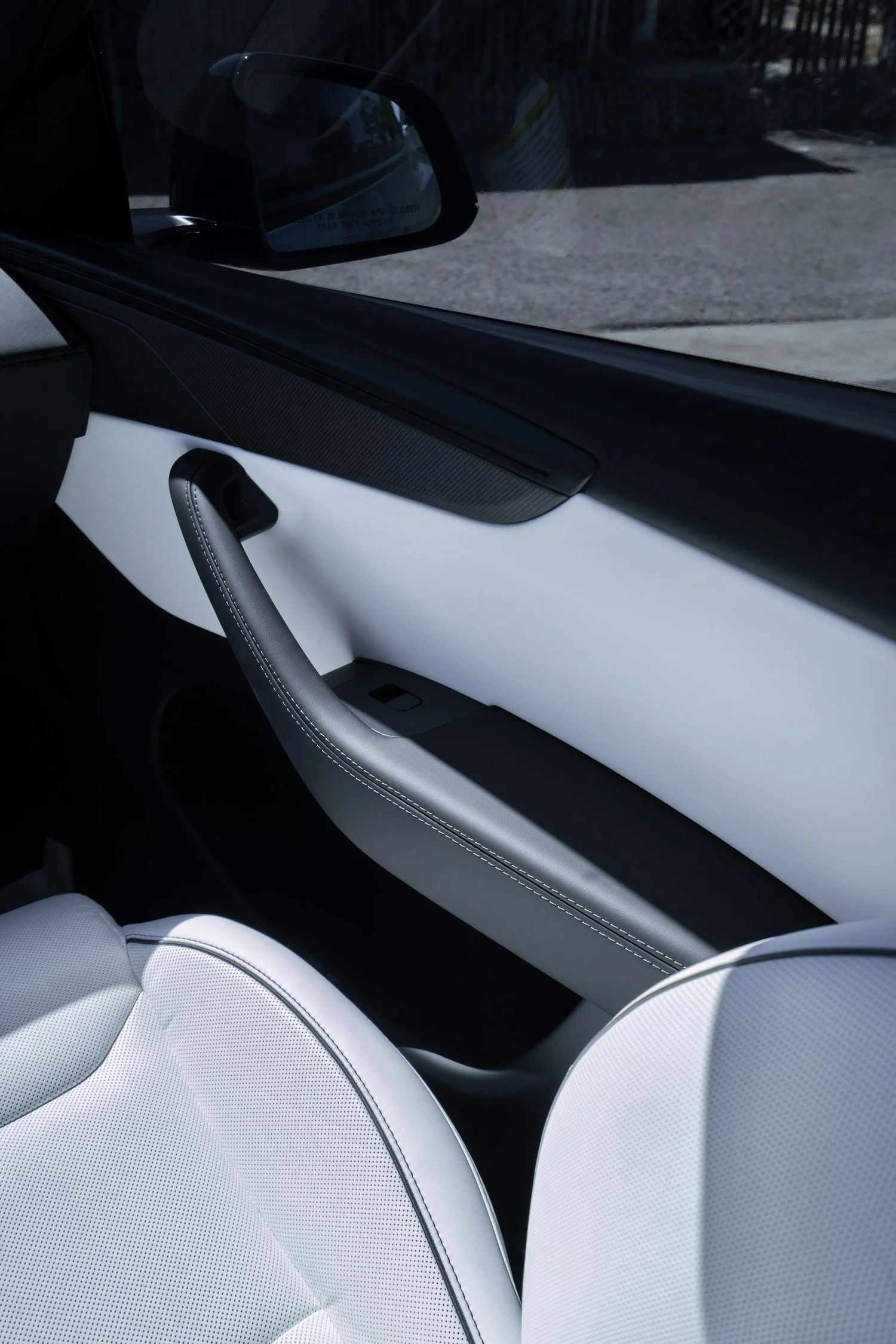 White seat and front door trim of the Tesla Model Y Performance beside its front side window