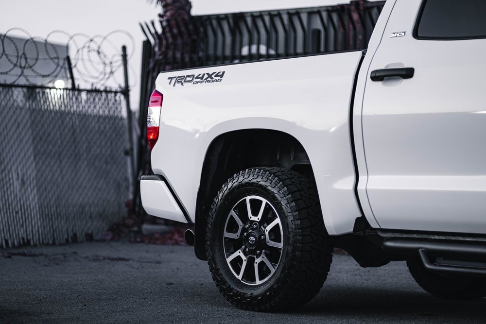 Horizontal side view of the Toyota Tundra Gloss White bed panel and rear wheel