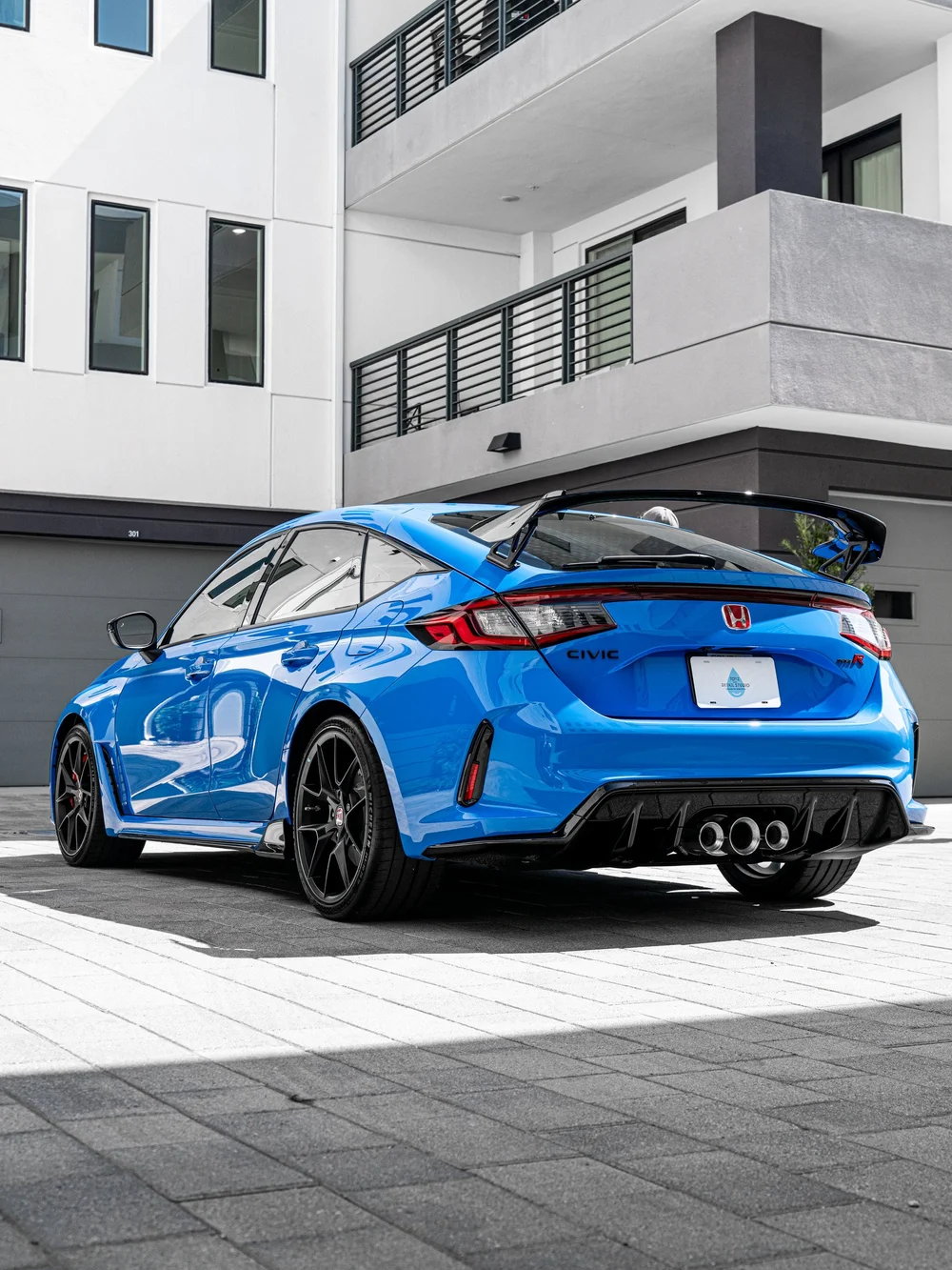 Low rear three-quarter view of a 2026 Honda Civic Type R in Boost Blue Pearl