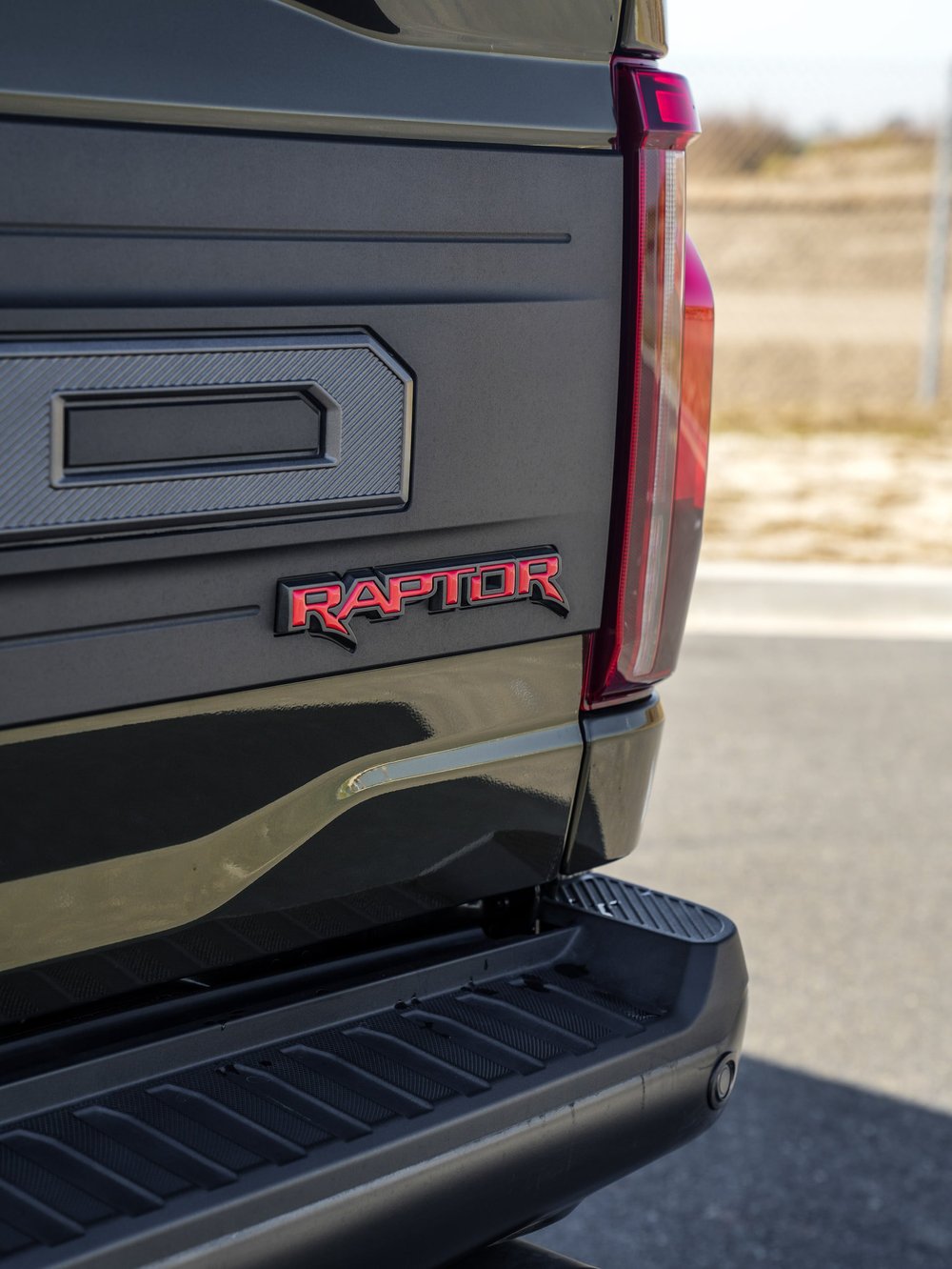 Black Ford F-150 Raptor, tailgate close-up with Raptor badge and rear step