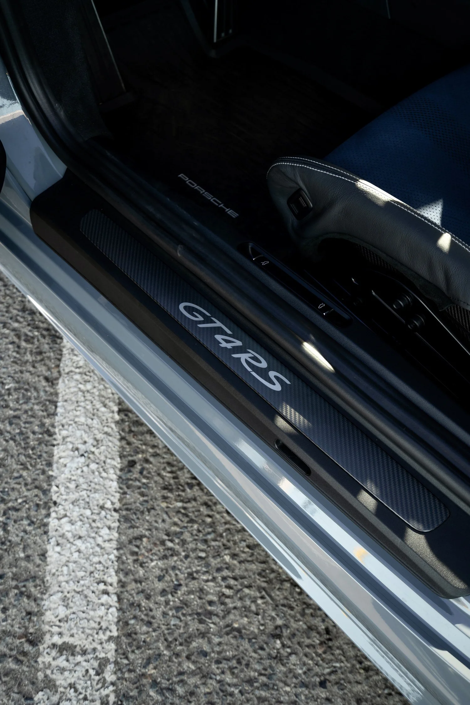 Carbon-fiber GT4 RS door sill beside an open doorway and blue seat insert.