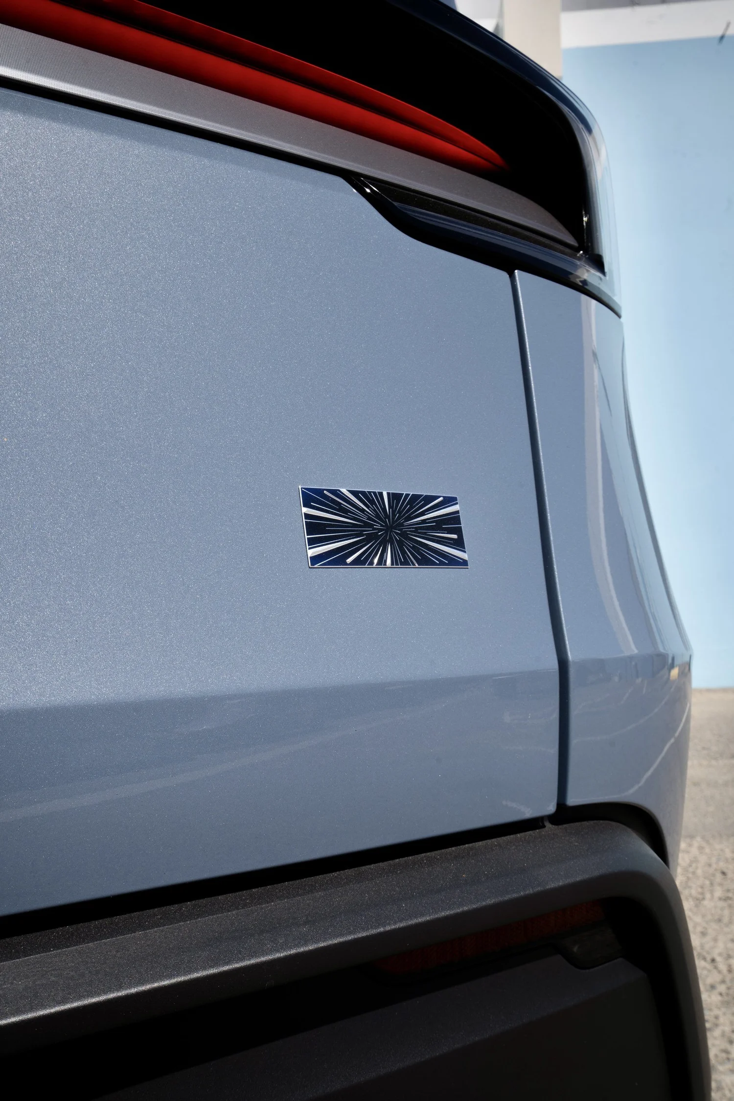 Close-up of the Model Y Performance rear badge on Glacier Blue paint below the rear light