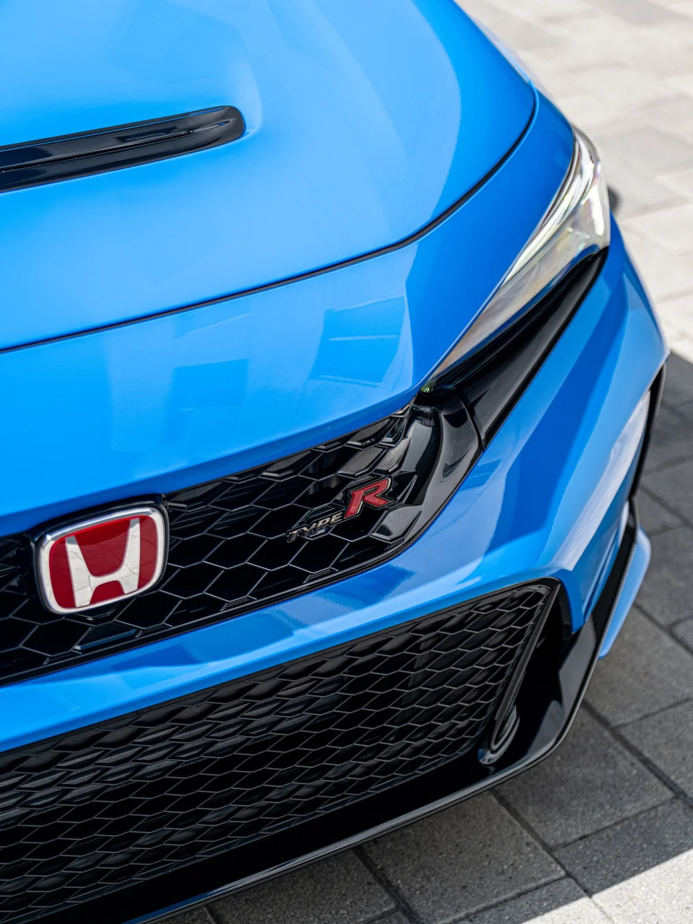 Close view of the front grille, red Honda badge and headlight on a Civic Type R