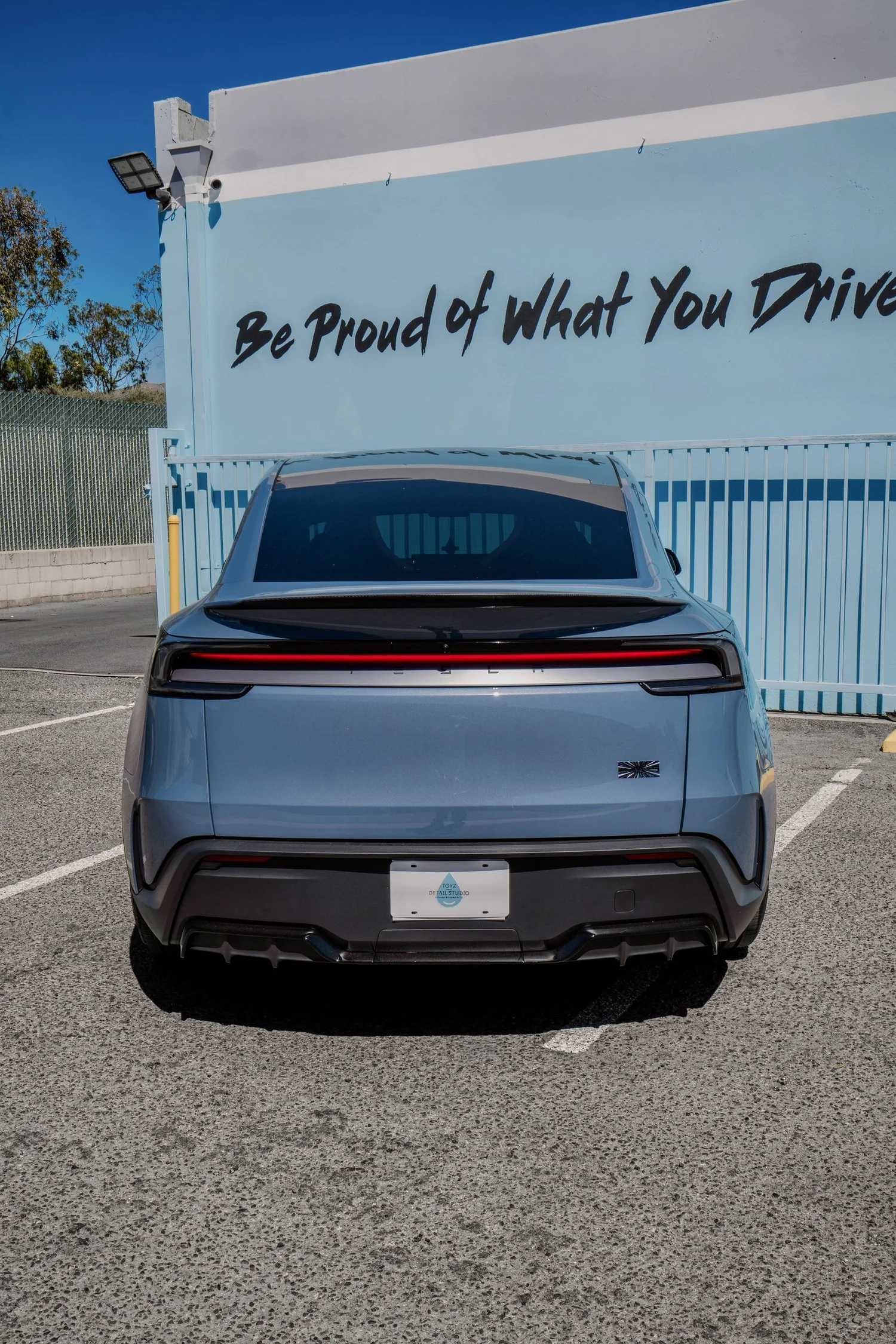 Rear view of the Glacier Blue Model Y Performance with its spoiler and full-width rear light