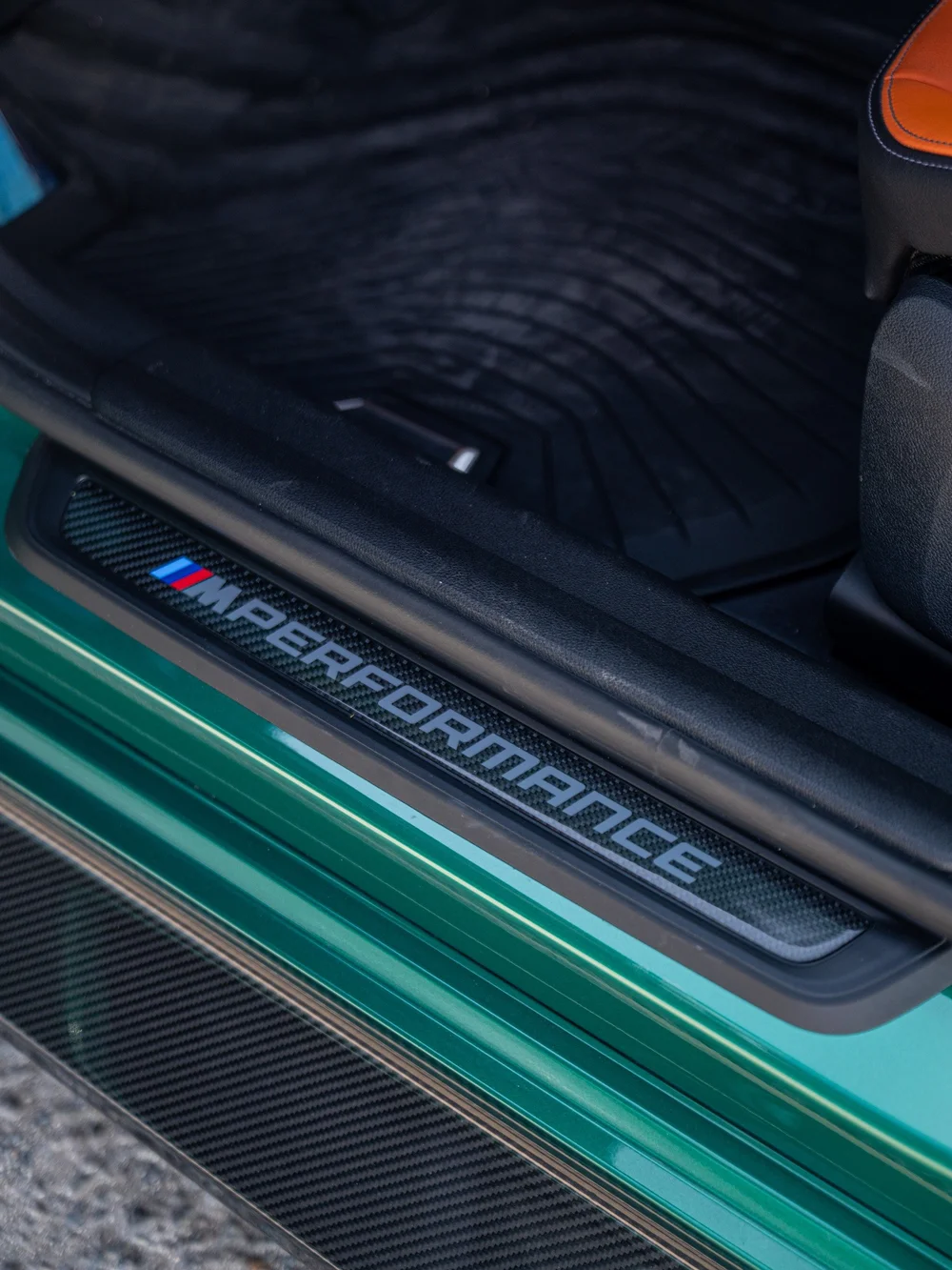 M Performance carbon door-sill trim inside the green M3 beside the exterior carbon side-skirt extension
