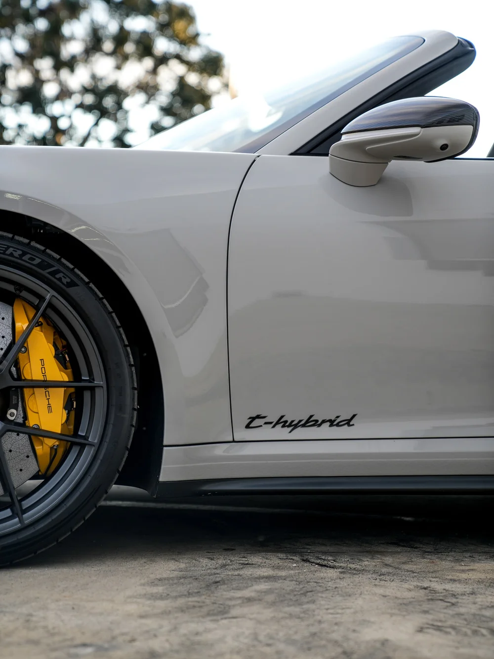 Light Porsche door, side mirror and front wheel beside the open Targa cabin