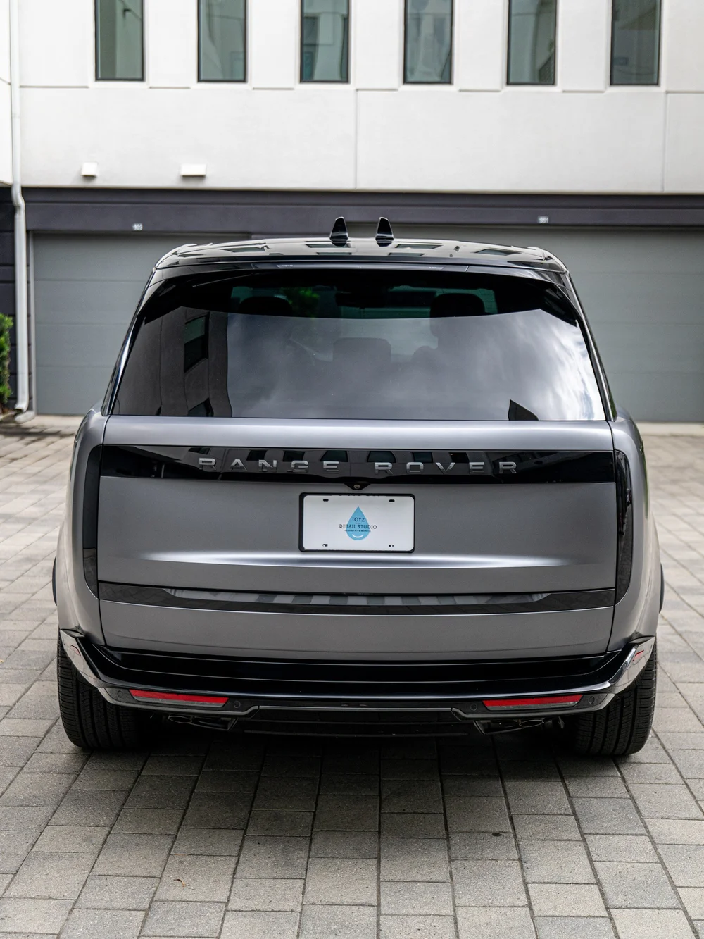 Straight-on rear view of the Range Rover LWB showing the tailgate, slim taillights, rear window and black lower bumper.