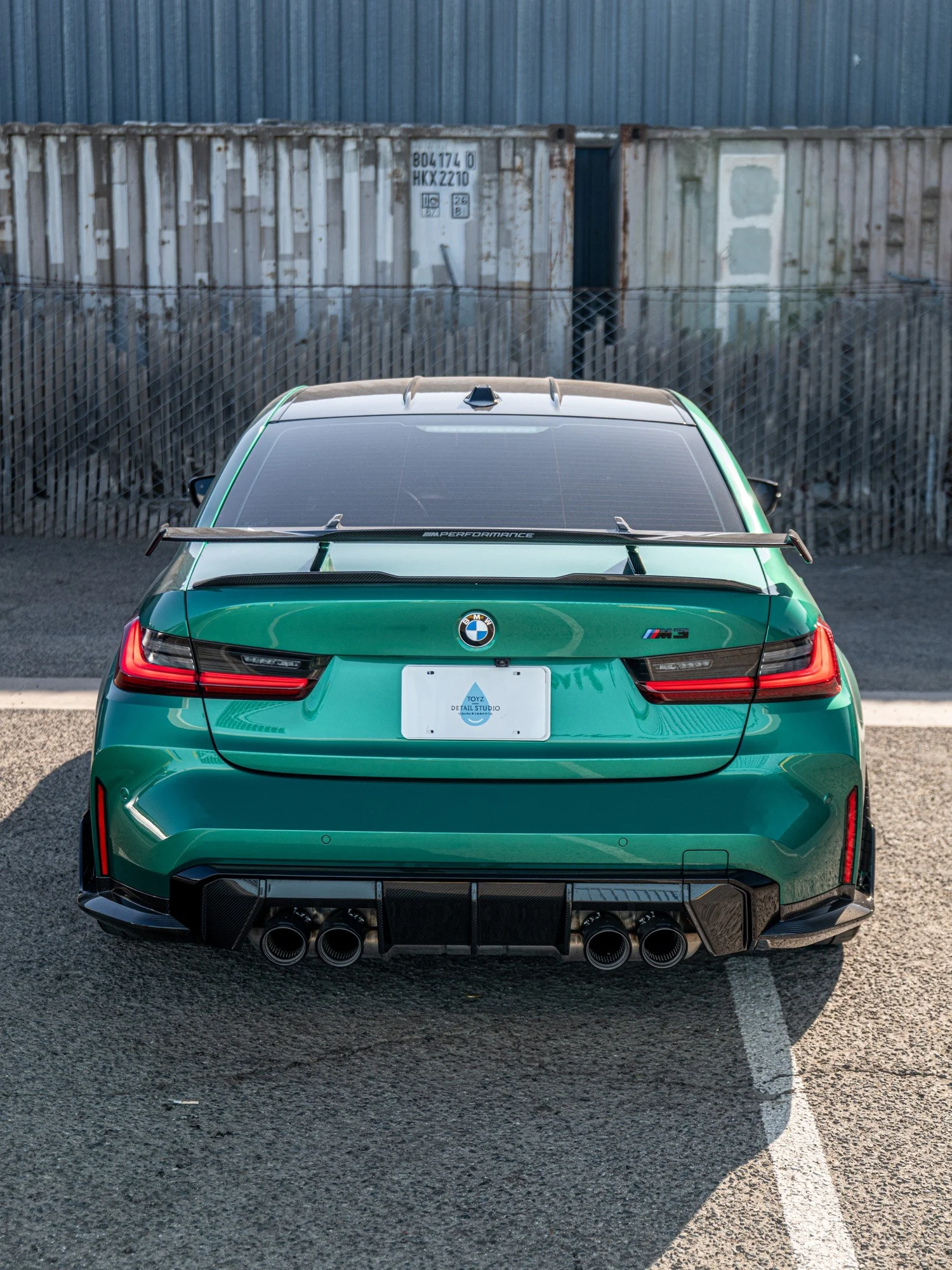 Straight rear view of the green G80 M3 showing its carbon wing, rear diffuser and four exhaust outlets