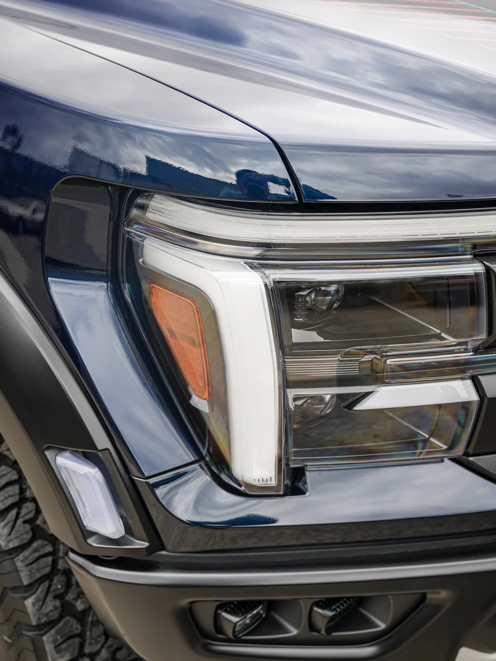 Dark Blue Ford F-150 Raptor, front headlight and grille corner close-up
