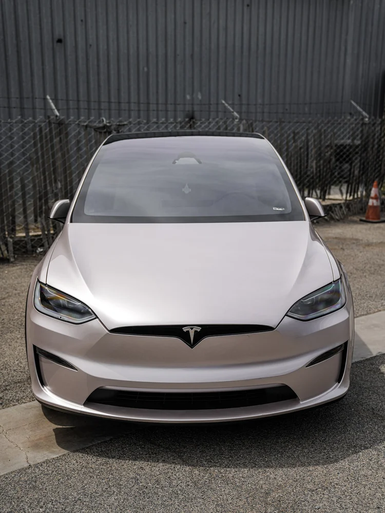 Complete centered front view of the Champagne Gold Model X showing both headlights and curved hood.
