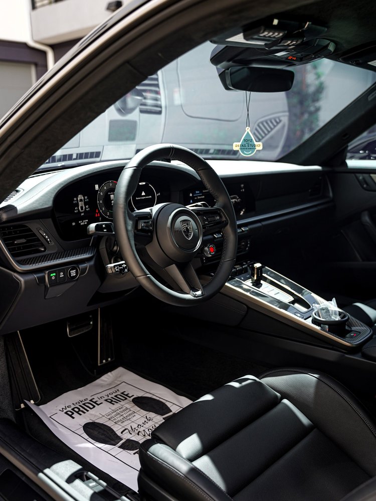 Turbo S steering wheel, dashboard and center console viewed through the open driver door.