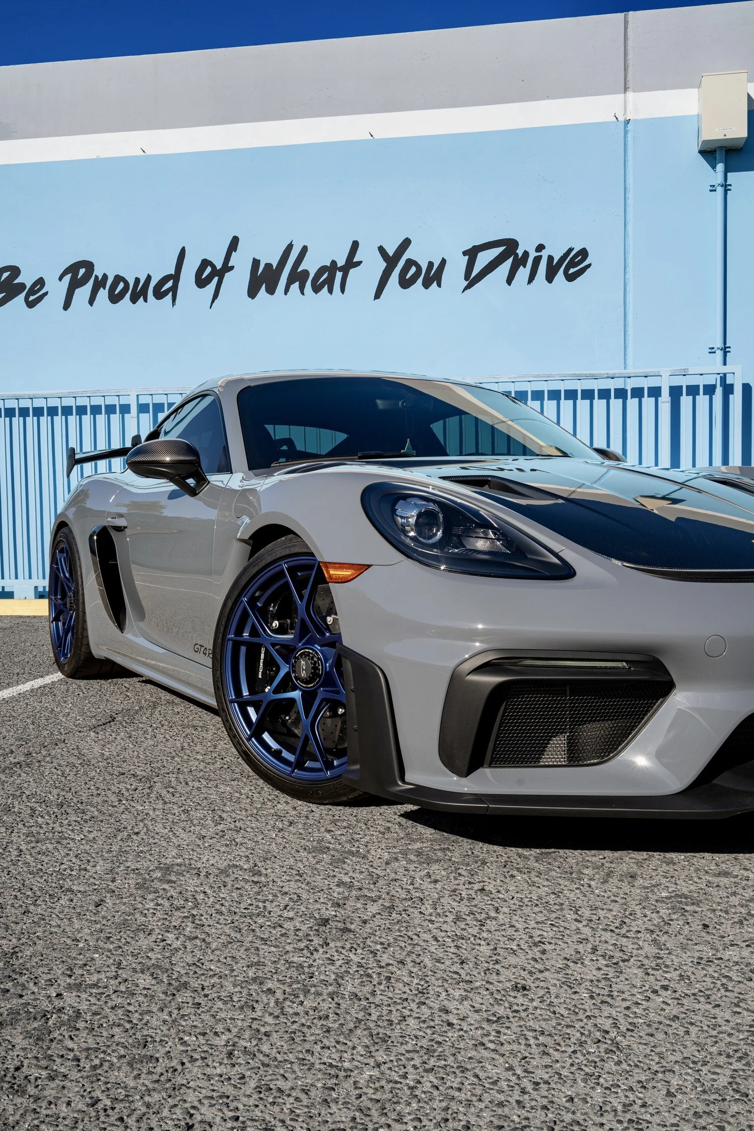 Low front-quarter detail of the GT4 RS blue front wheel, Arctic Grey fender, headlight and carbon mirror.