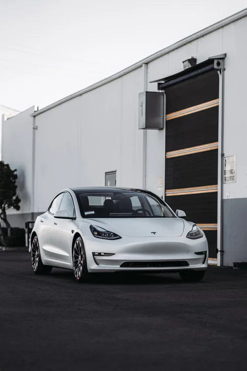 Portrait front three-quarter view of the complete Tesla Model 3 with 3M 2080 Satin Pearl White vinyl and closed doors